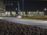 an empty road at night outside of the large industrial area of the city with lights in the background