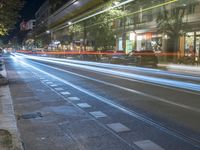 a night time shot of an empty street at the edge of a busy city street