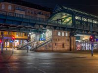 the empty street is filled with people walking and biking under an overpass at night