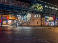 the empty street is filled with people walking and biking under an overpass at night