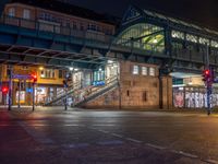 the empty street is filled with people walking and biking under an overpass at night