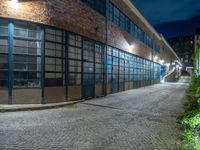 some dark blue windows in an industrial building with no one on the street to the right