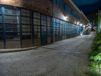 some dark blue windows in an industrial building with no one on the street to the right