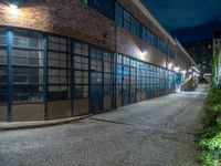 some dark blue windows in an industrial building with no one on the street to the right