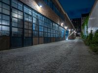 some dark blue windows in an industrial building with no one on the street to the right