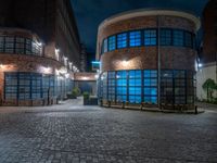 some dark blue windows in an industrial building with no one on the street to the right