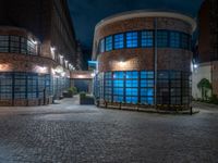 some dark blue windows in an industrial building with no one on the street to the right