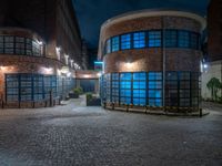 some dark blue windows in an industrial building with no one on the street to the right