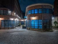 some dark blue windows in an industrial building with no one on the street to the right