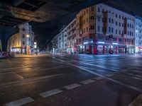 the empty street is filled with people walking and biking under an overpass at night