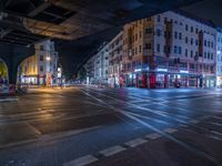 the empty street is filled with people walking and biking under an overpass at night