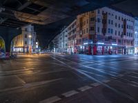 the empty street is filled with people walking and biking under an overpass at night