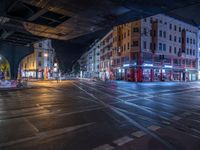 the empty street is filled with people walking and biking under an overpass at night