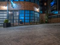 some dark blue windows in an industrial building with no one on the street to the right