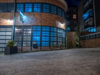 some dark blue windows in an industrial building with no one on the street to the right