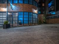 some dark blue windows in an industrial building with no one on the street to the right