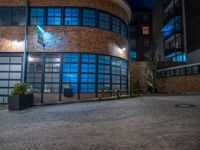 some dark blue windows in an industrial building with no one on the street to the right