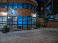 some dark blue windows in an industrial building with no one on the street to the right