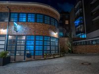 some dark blue windows in an industrial building with no one on the street to the right