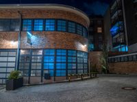 some dark blue windows in an industrial building with no one on the street to the right