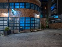 some dark blue windows in an industrial building with no one on the street to the right