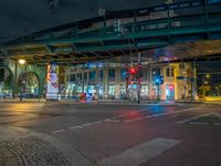 the empty street is filled with people walking and biking under an overpass at night