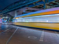 the empty street is filled with people walking and biking under an overpass at night