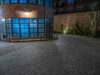 some dark blue windows in an industrial building with no one on the street to the right