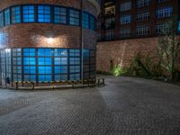 some dark blue windows in an industrial building with no one on the street to the right