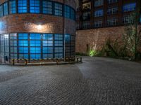 some dark blue windows in an industrial building with no one on the street to the right