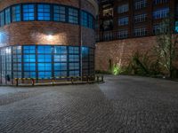 some dark blue windows in an industrial building with no one on the street to the right