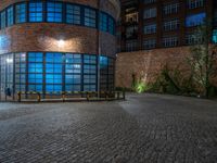 some dark blue windows in an industrial building with no one on the street to the right