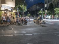 a crowd of people stand at a curb and wait for a car to cross the street