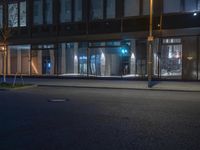 a person is standing on the sidewalk of a building at night as a traffic light illuminates