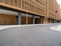 the empty street and entrance of an office building with balconies and trees on the side