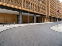 the empty street and entrance of an office building with balconies and trees on the side