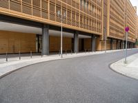 the empty street and entrance of an office building with balconies and trees on the side