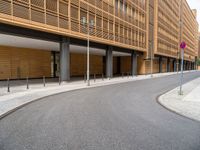 the empty street and entrance of an office building with balconies and trees on the side