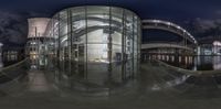 a night shot of a futuristic structure in a city with glass on each side of the doors