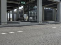 a parking area at an office in the city has glass walls and pillars on both sides of it