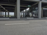 a parking area at an office in the city has glass walls and pillars on both sides of it