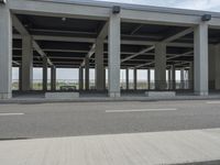 a parking area at an office in the city has glass walls and pillars on both sides of it