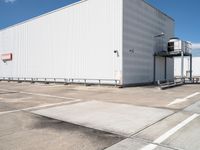 a large white warehouse building with windows on a sunny day in the parking lot for commercial and industrial vehicles