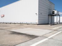 a large white warehouse building with windows on a sunny day in the parking lot for commercial and industrial vehicles