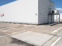 a large white warehouse building with windows on a sunny day in the parking lot for commercial and industrial vehicles