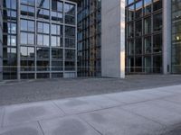 the empty sidewalk is surrounded by some office buildings on the other side of the road