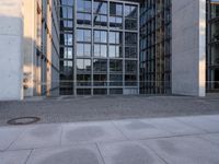 the empty sidewalk is surrounded by some office buildings on the other side of the road