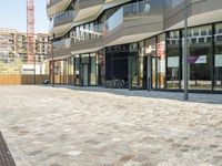 a sidewalk next to buildings in a city with many windows and doors that are open