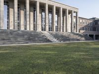 large, gray stone building with stairs going up to it and grass growing around the area