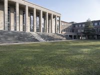 large, gray stone building with stairs going up to it and grass growing around the area